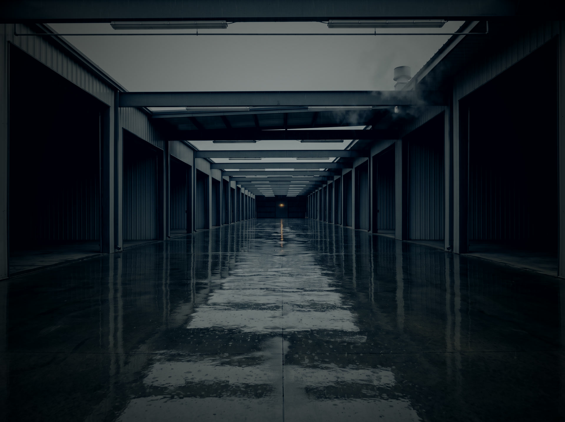 A row of lit factory bays at night under cold blue light